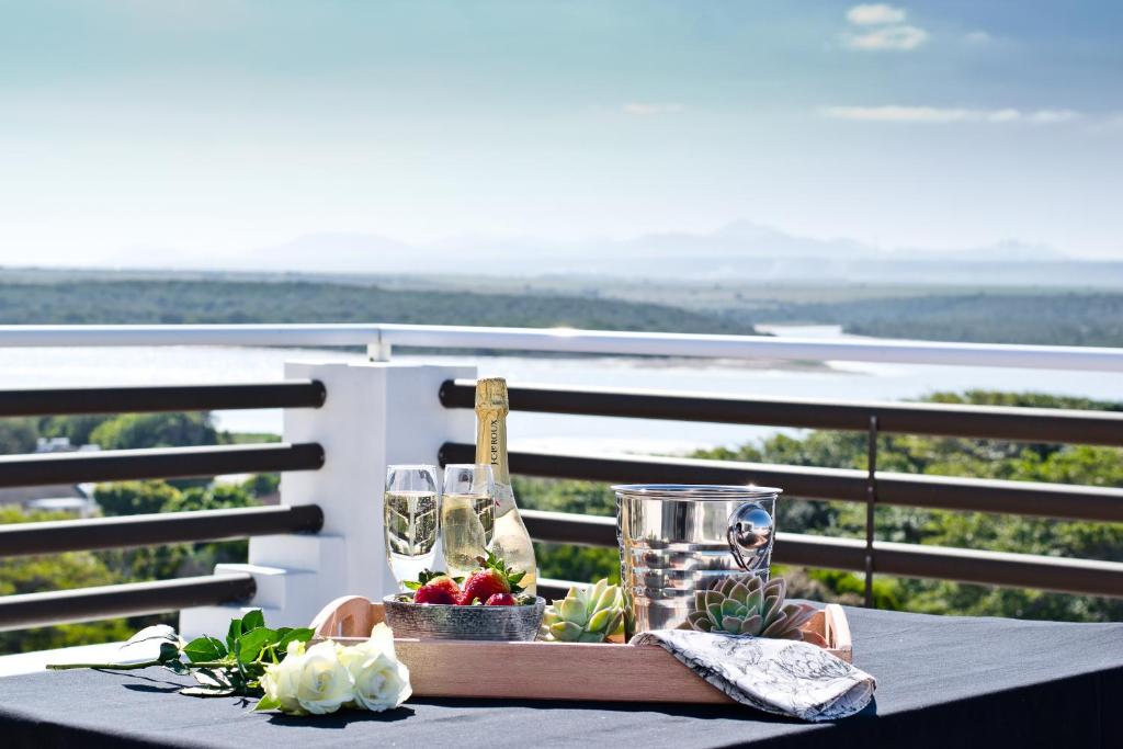a table with a tray of wine glasses and flowers at Aguia-Vista Couples Haven, Views, Pool, Beach Walk in Jeffreys Bay