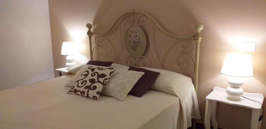 a bedroom with a white bed with two lamps at Giardini di Marzo in Felline