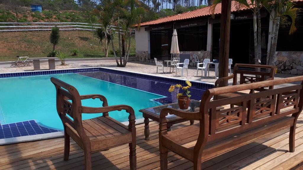 a pool with two wooden benches next to a table and a table at Pousada Kart Clube in São João del Rei