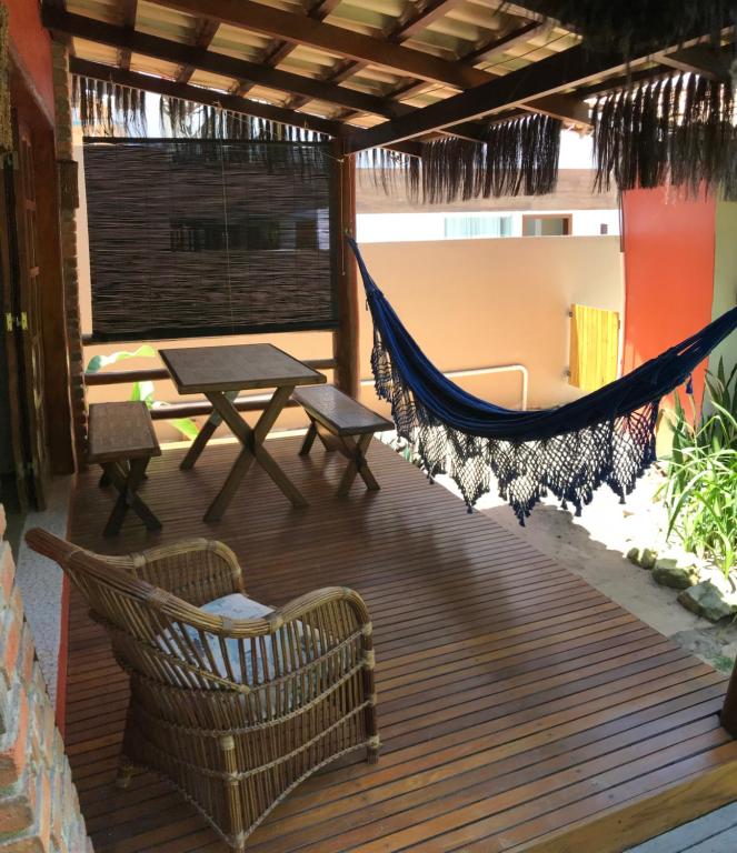 a hammock on a deck with a table and chairs at Pousada Capitão Gancho in Barra Grande
