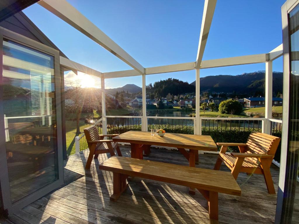 a wooden table and chairs on a deck with a view at *** LAKE VILLA 457 *** in Hanmer Springs
