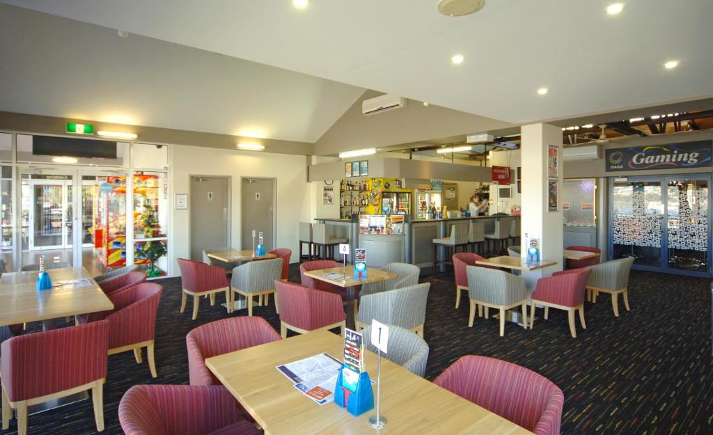 a restaurant with tables and chairs and a bar at Argosy Motor Inn in Devonport