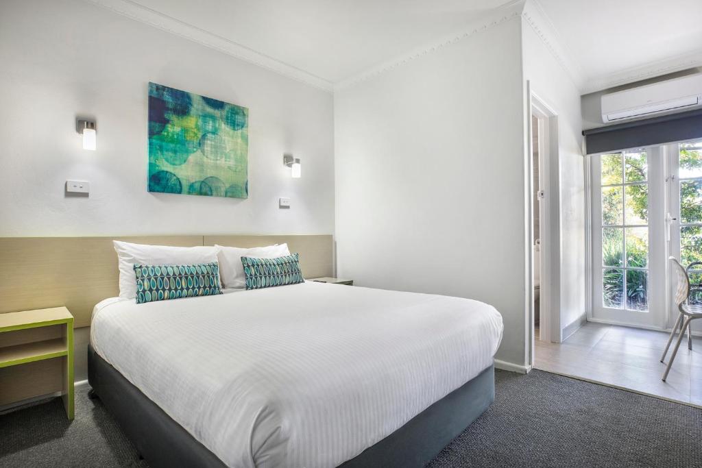 um quarto com uma grande cama branca e uma janela em Nightcap at Skyways Hotel em Melbourne