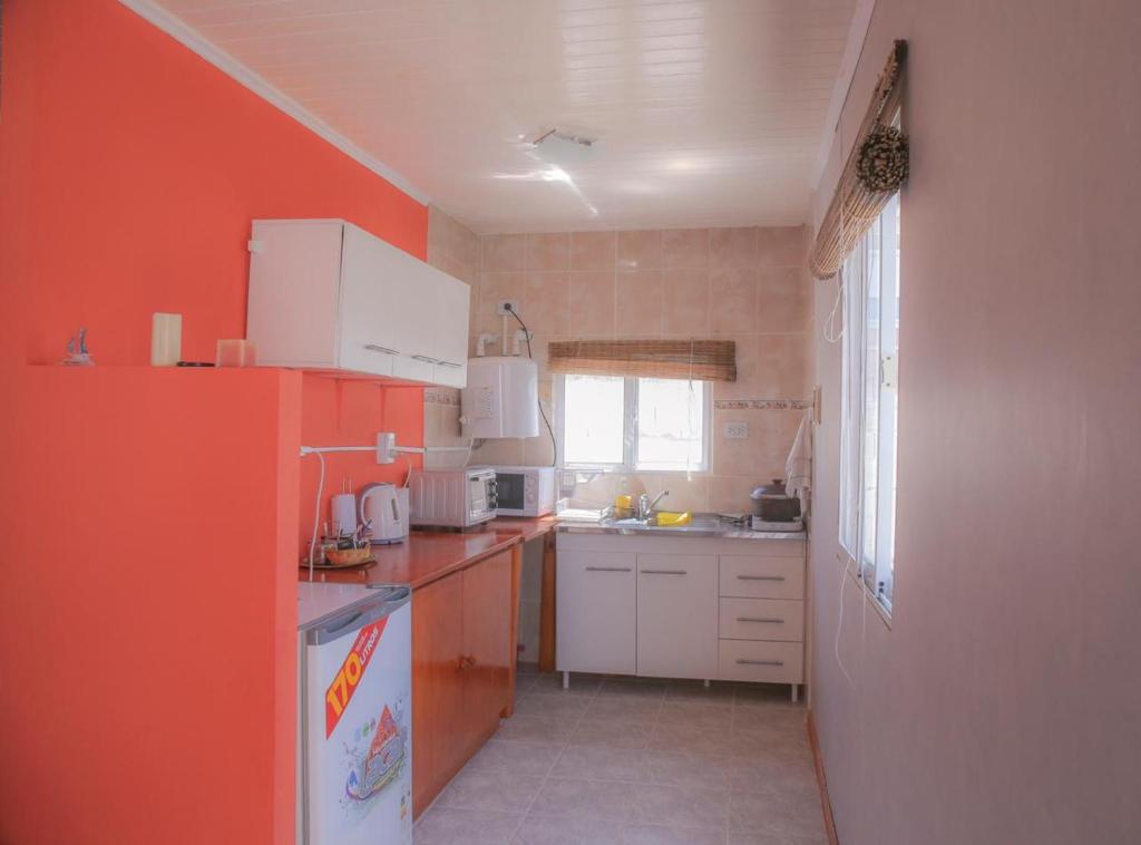 een kleine keuken met oranje muren en witte apparaten bij Casa en Claromecó La Alegria in Balneario Claromecó