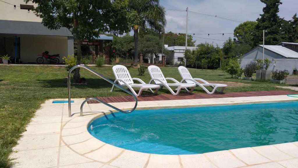 - deux chaises blanches installées à côté de la piscine dans l'établissement COMPLEJO Aires del Ñapindá, à Paraná