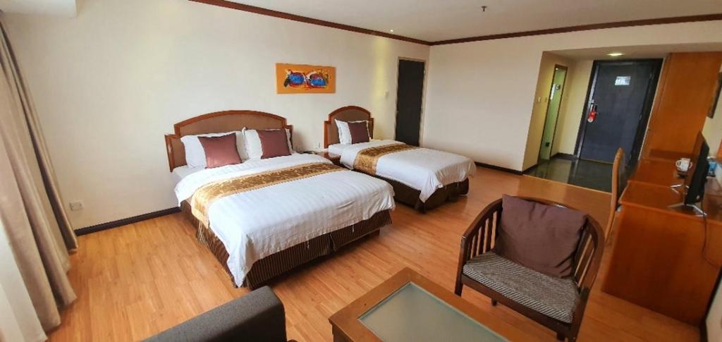 a hotel room with two beds and a chair at Kemena Plaza Hotel in Bintulu