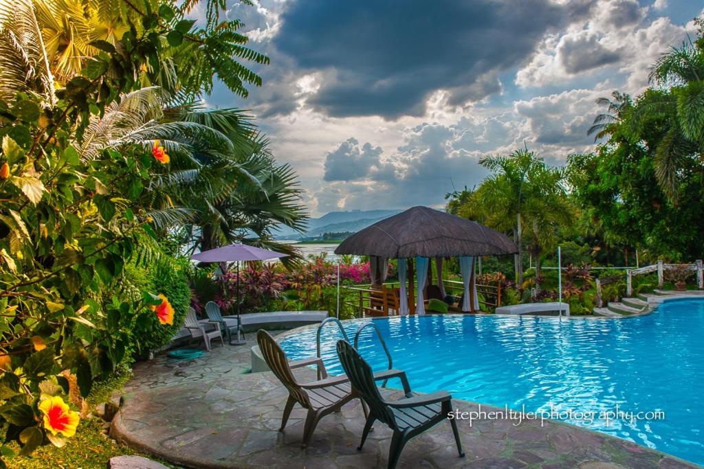 una piscina con due sedie e un ombrellone di AWILIHAN PRIVATE PARADISE RESORT a Ambulong