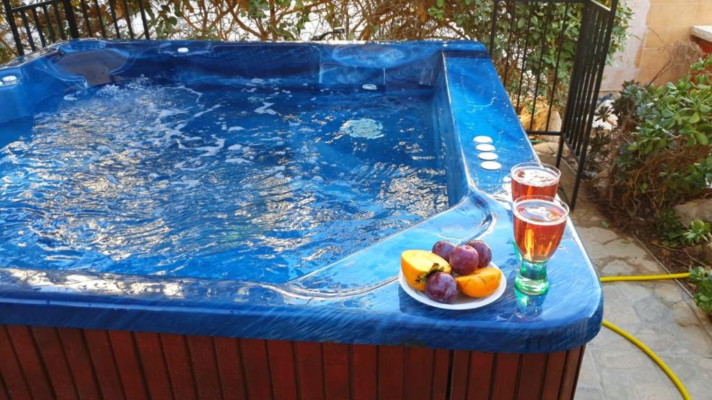 a pool with a bowl of fruit and two glasses of juice at Dead Sea-Sunny Holidays Village & SPA in Arad