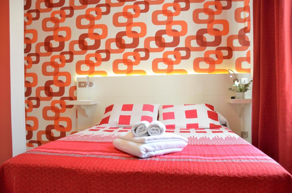 1 dormitorio con 1 cama roja y blanca y toallas en Far Home Plaza Mayor, en Madrid