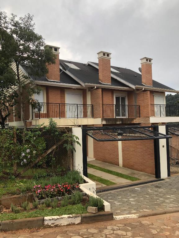 a house with a balcony and a courtyard with flowers at Chalé Centro de Monte Verde in Monte Verde