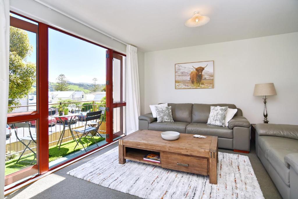 Una sala de estar con un sofá y una mesa de café. en Central Akaroa Retreat - Balcony and Parking -Tumeke Akaroa, en Akaroa