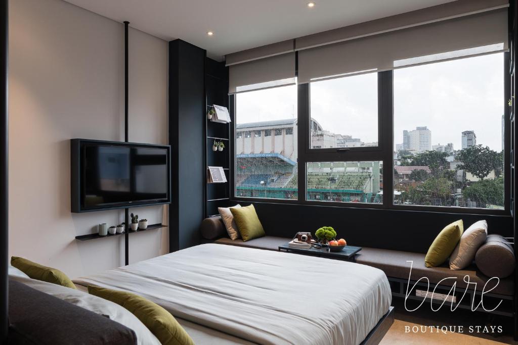 a bedroom with a bed and a flat screen tv at Bare Chic - Bare Boutique Stays in Ho Chi Minh City