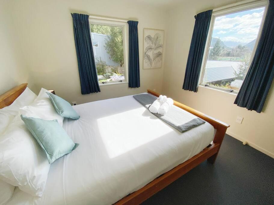 a bedroom with a large white bed with blue pillows at Hideaway Rima - in the CBD in Queenstown