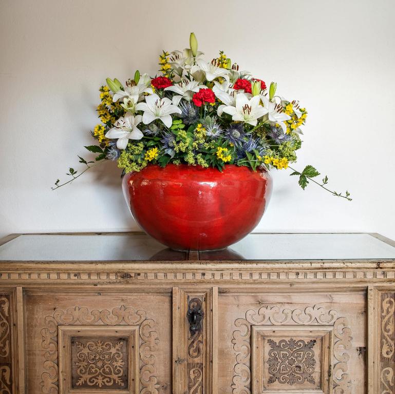 a red vase with flowers on top of a cabinet at Hotel Privata in Sils Maria