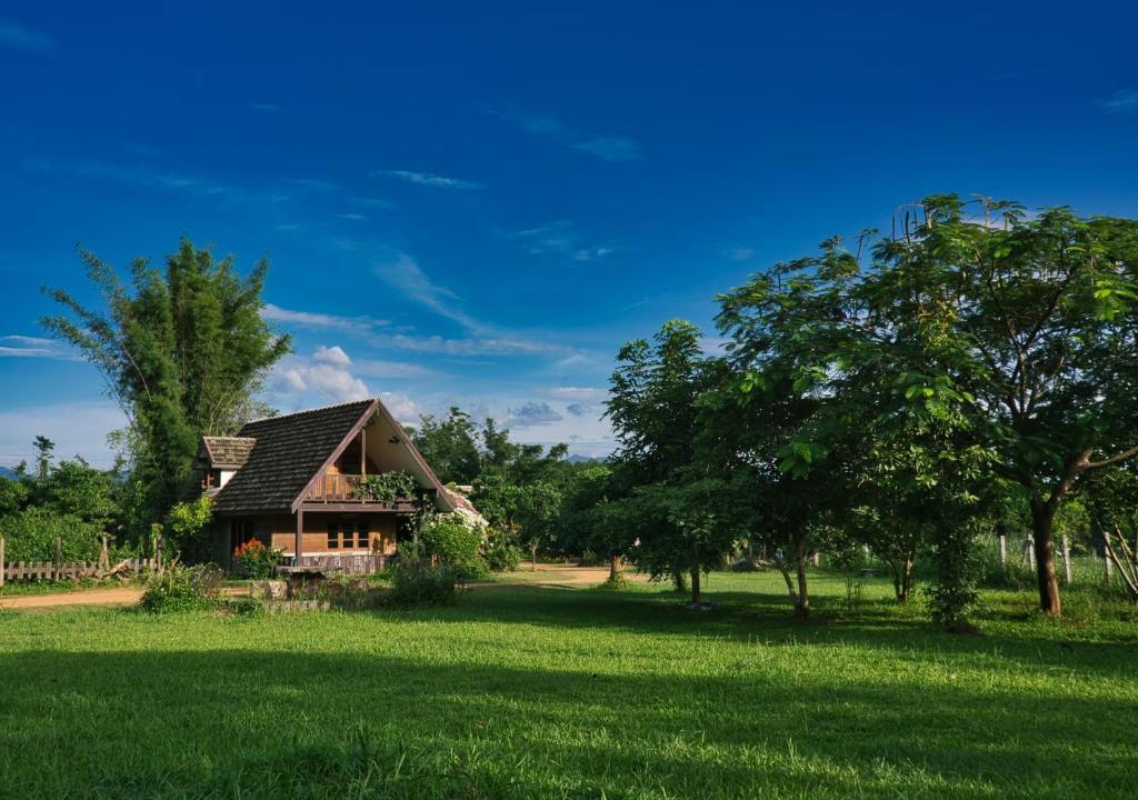a house in the middle of a field with trees at Cozycomo Chiang Dao - Wiang Mek in Chiang Dao