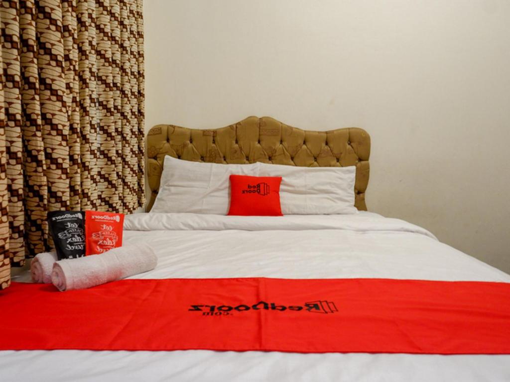 a bed with two red pillows and a red blanket at RedDoorz near Tugu Yogyakarta in Yogyakarta