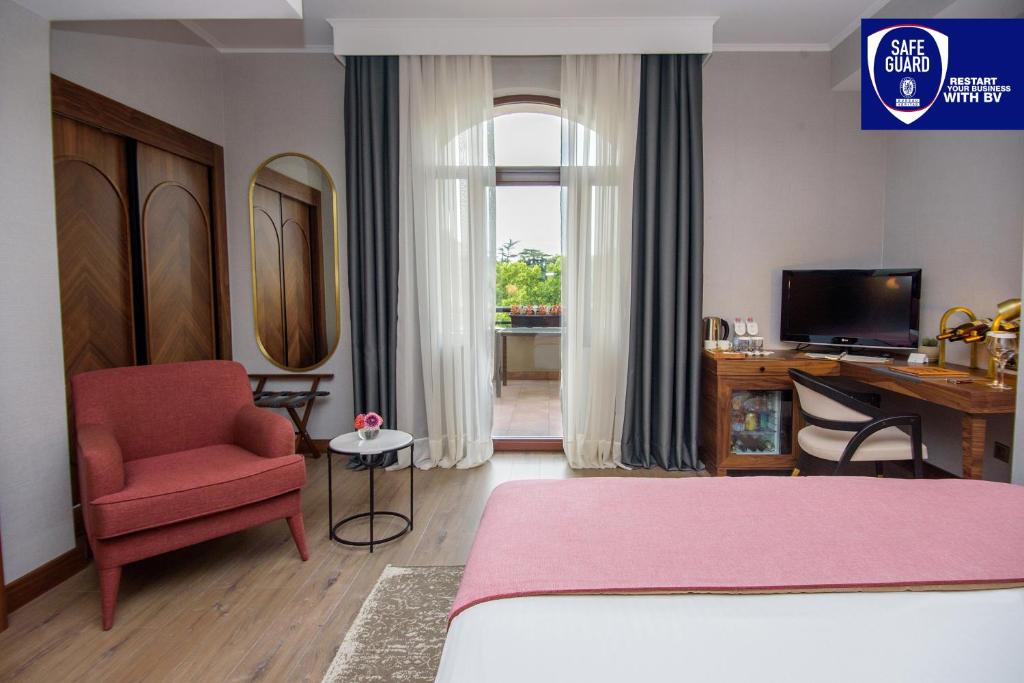 a bedroom with a bed and a chair and a desk at Tiflis Palace in Tbilisi City