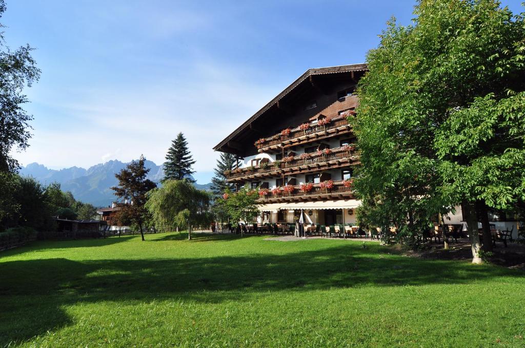 a large building with a green lawn in front of it at Kaiserhotel Kitzbühler Alpen in Oberndorf in Tirol