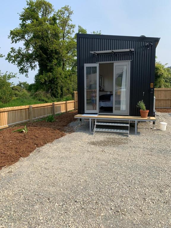 a black tiny house with a bench in a yard at Blackball Tinyhouses in Blackball