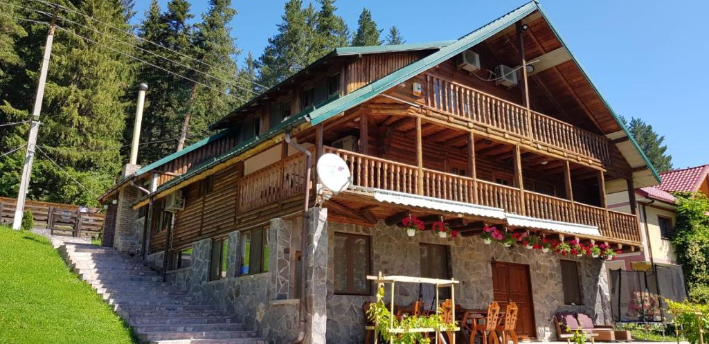 a log house with a porch and a balcony at Cabana Soveja in Soveja