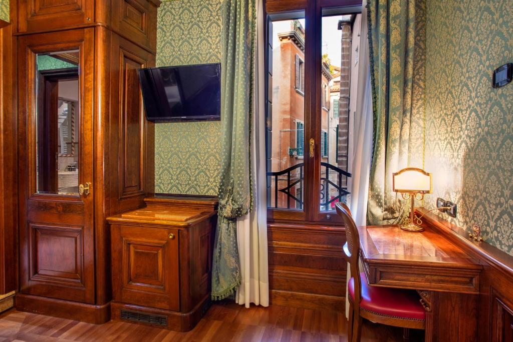 Pokój z drewnianym stołem, biurkiem i oknem w obiekcie Palazzina Veneziana w Wenecji