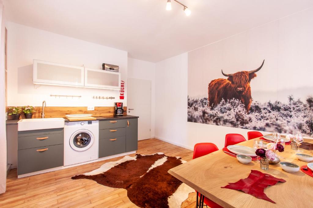 eine Küche und ein Esszimmer mit einem Tisch und einer Kuh an der Wand in der Unterkunft Modern & spacious apartment for up to 8 persons in Würzburg
