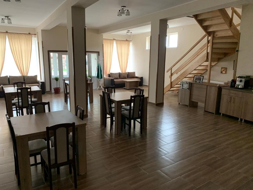 ein Wohnzimmer mit Tischen, Stühlen und einer Treppe in der Unterkunft Pensiunea Pisc in Tuştea
