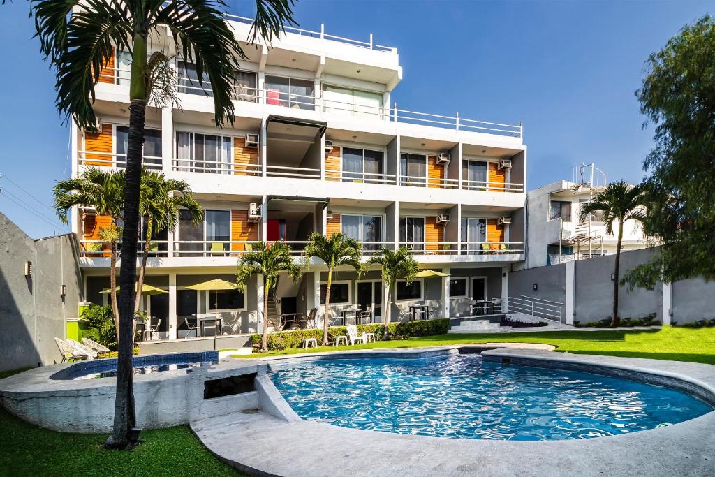 a hotel with a swimming pool in front of a building at Collection O Hotel Mango,Six Flags Hurricane Harbor Oaxtepec in Oaxtepec