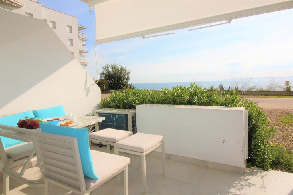 un patio con mesas y sillas y vistas al océano en Global Immo 1037 MEDA CHICA BX, en Roses