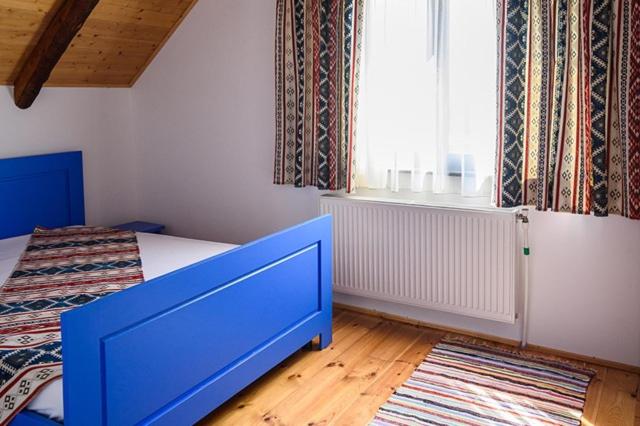 a bedroom with a blue bed and a window at Conacul lui Radu in Făgăraş