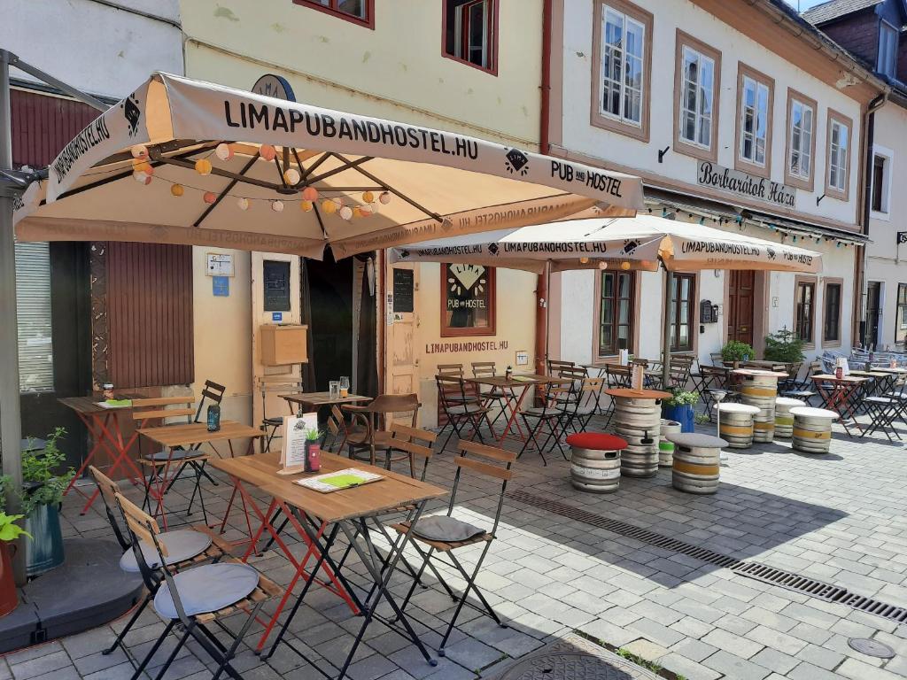 un restaurante al aire libre con mesas, sillas y sombrillas en Borbarátok Háza, en Győr