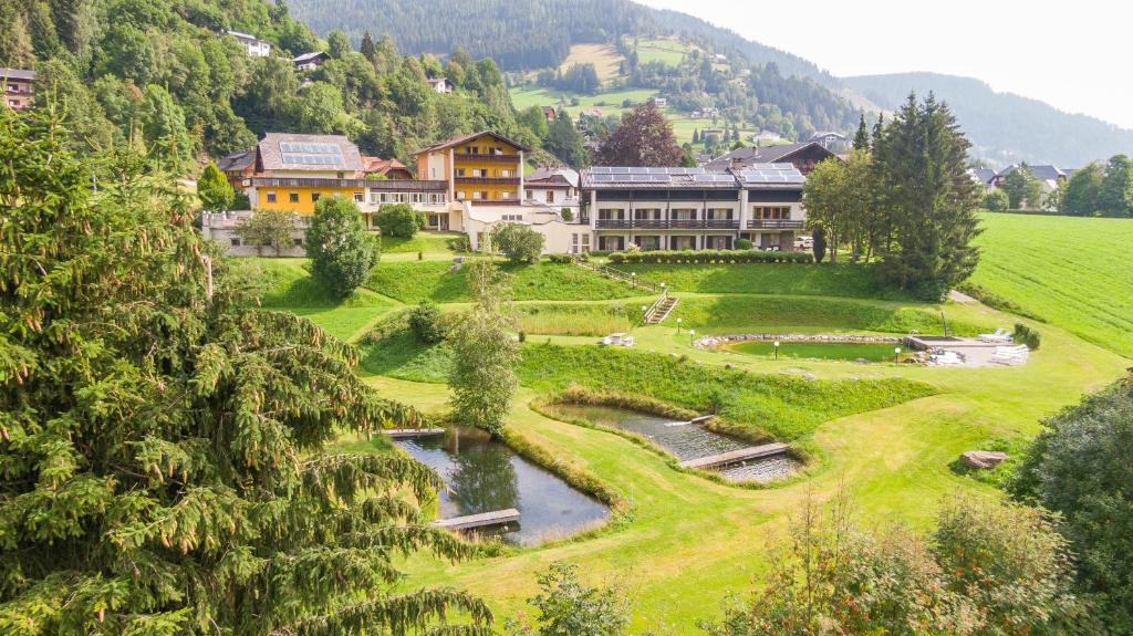a resort in the mountains with a pond and trees at Hotel Guesthouse Dalnig in Bad Kleinkirchheim