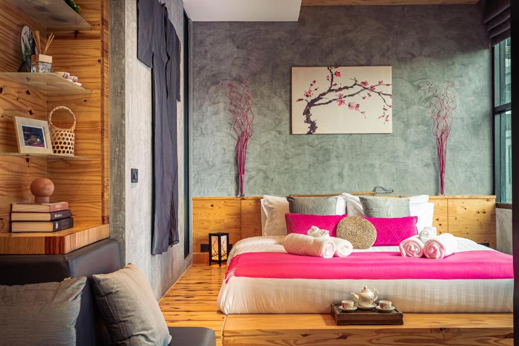Cozy design studio near Nai Harn beach في شاطئ نايهان: غرفة نوم مع سرير كبير مع وسائد وردية