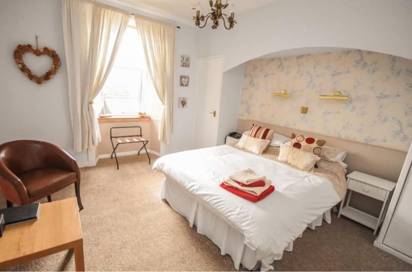 a bedroom with a large white bed and a chair at Burntisland Sands Hotel in Burntisland