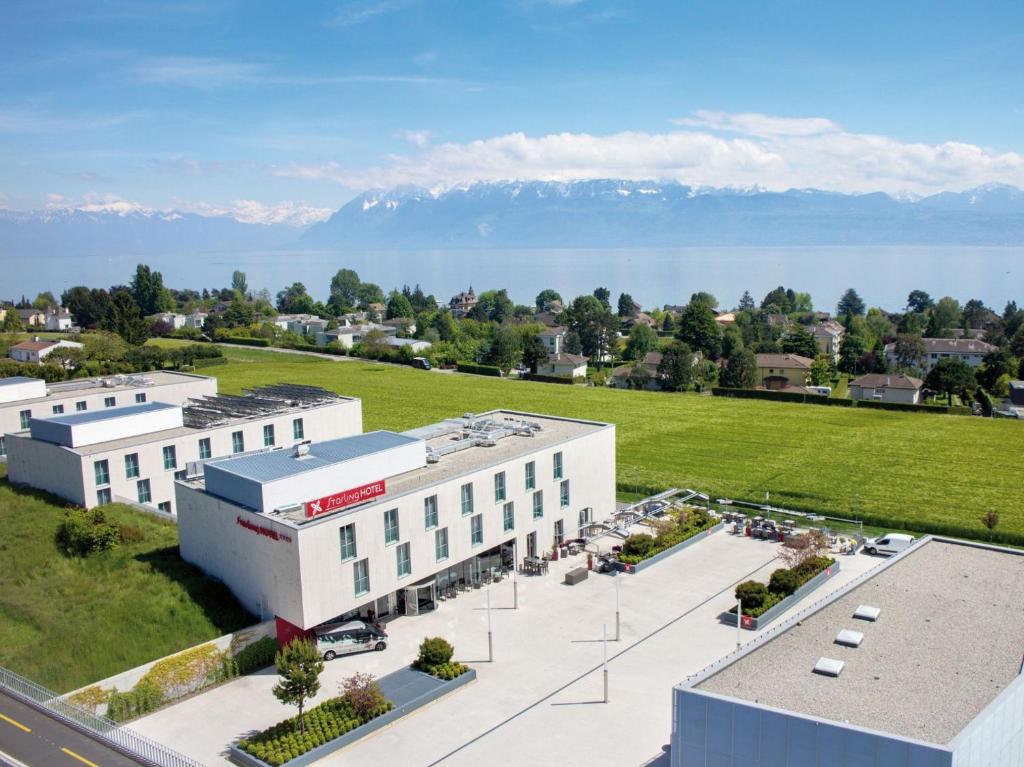 an aerial view of a large white building with mountains in the background at Starling Hotel Lausanne in Lausanne