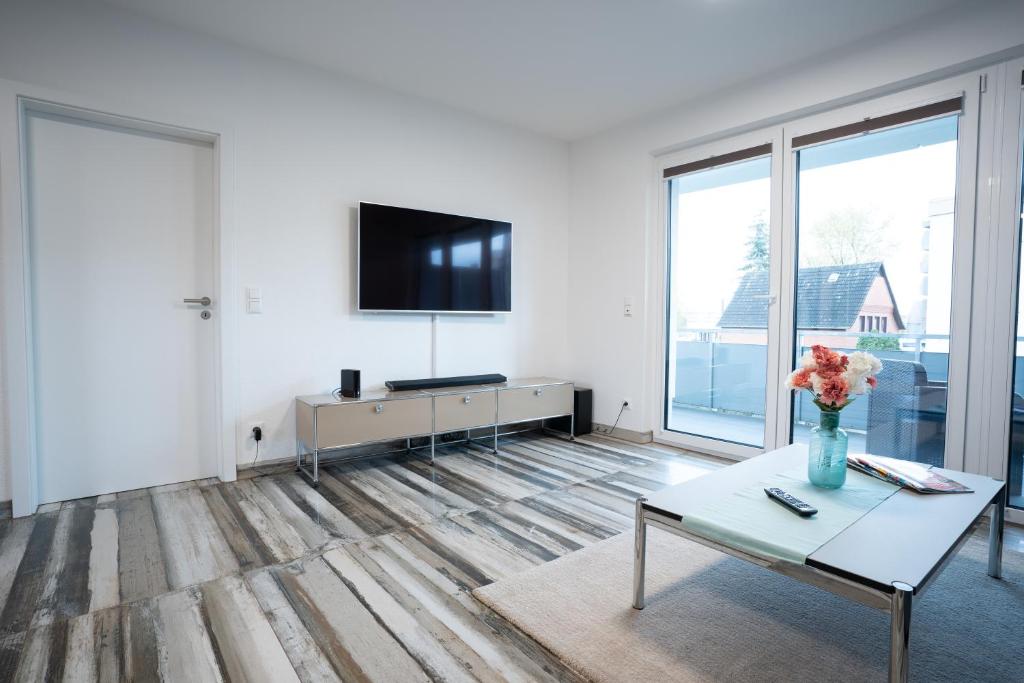 ein Wohnzimmer mit einem TV und einer Vase aus Blumen in der Unterkunft Apartement Laatzen nähe Messe in Hannover