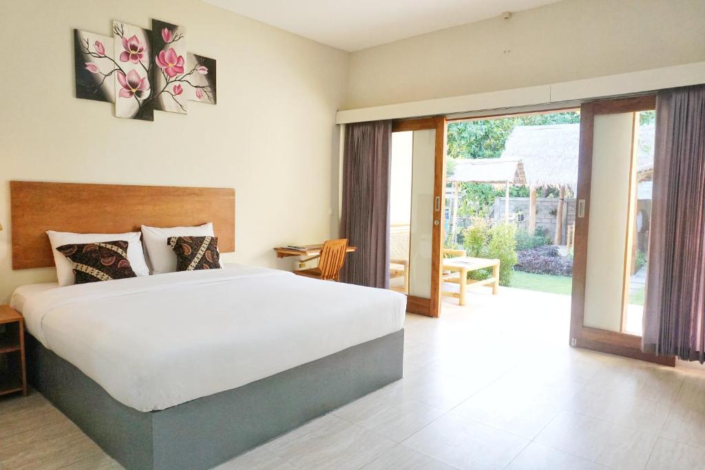 a bedroom with a large bed and a large window at sammy cottage senggigi in Mangsit