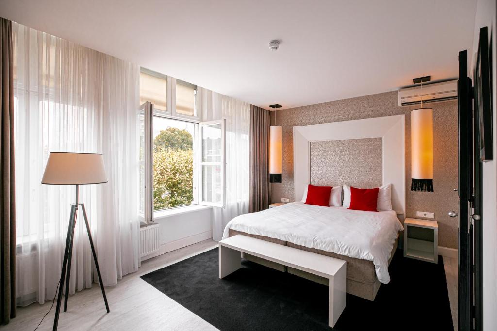 een slaapkamer met een bed met rode kussens en een raam bij Le Theatre in Maastricht