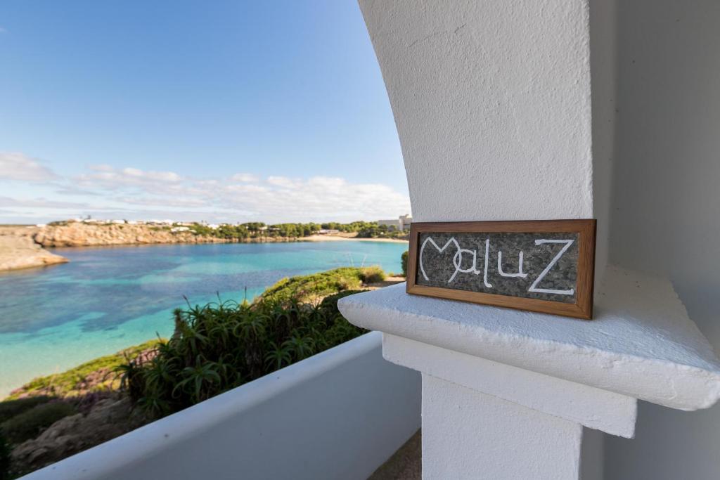 a sign on a balcony with a view of the ocean at Maluz in Arenal d'en Castell