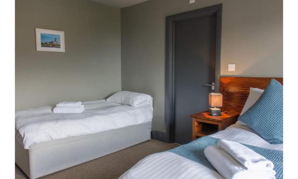 a bedroom with two beds and a table with a lamp at The Wellwood in Amble