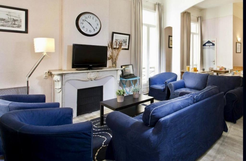 a living room with blue chairs and a fireplace at HOTEL SYLVABELLE in Marseille