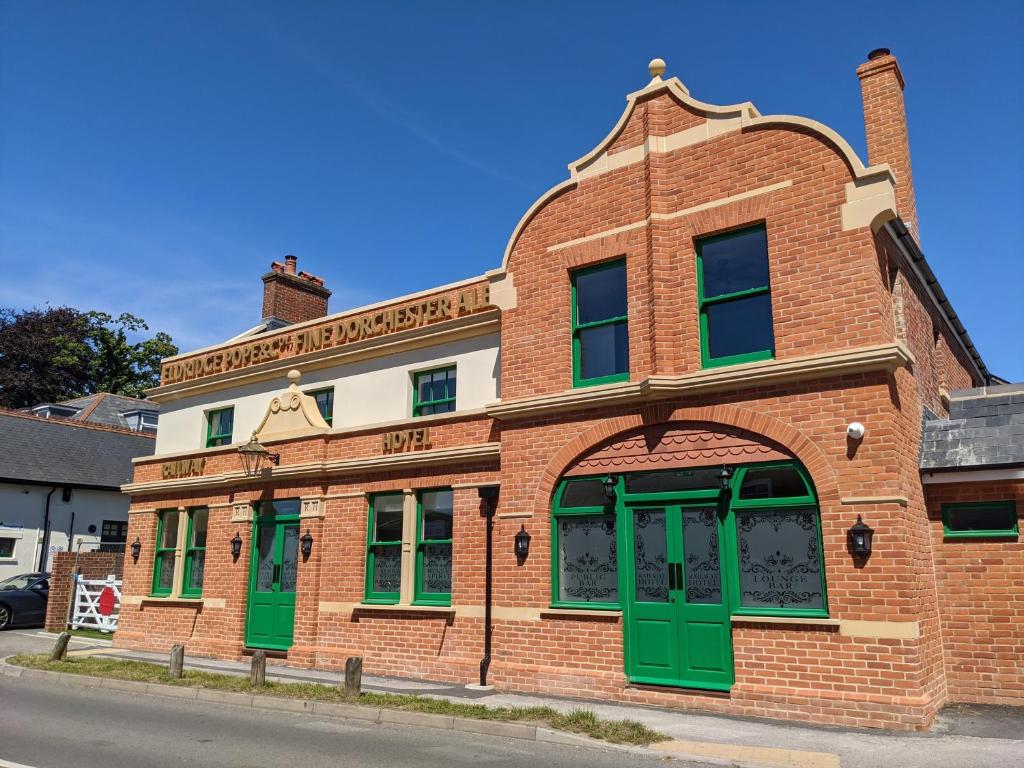 um antigo edifício de tijolos com portas verdes numa rua em Railway Hotel em Fordingbridge