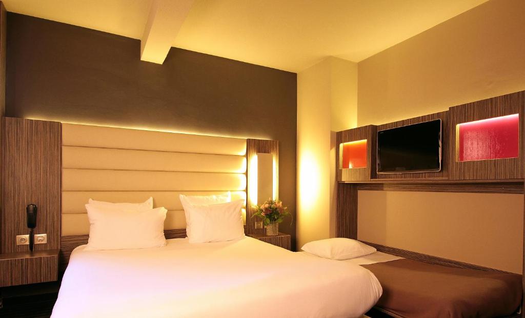 a hotel room with two beds and a flat screen tv at Hôtel de Brienne in Toulouse