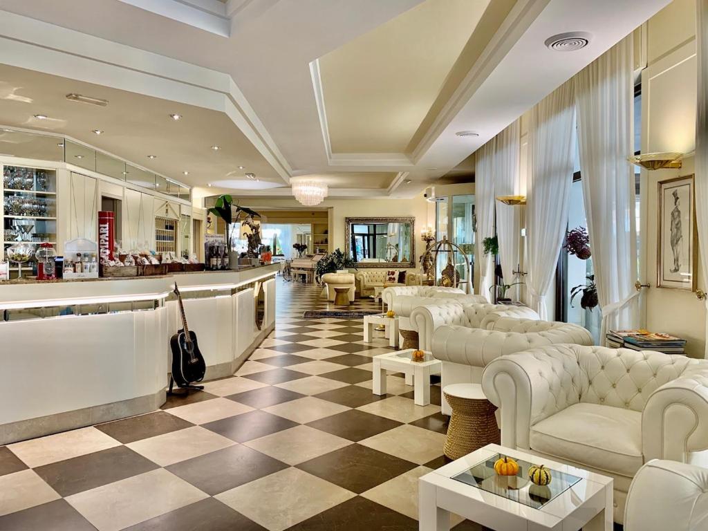 un vestíbulo con sofás blancos y suelo a cuadros en Hotel Brescia & Apartments, en Darfo Boario Terme