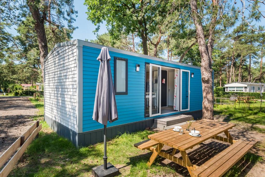 a blue tiny house with a picnic table and an umbrella at Chalet O'hara in Bilthoven