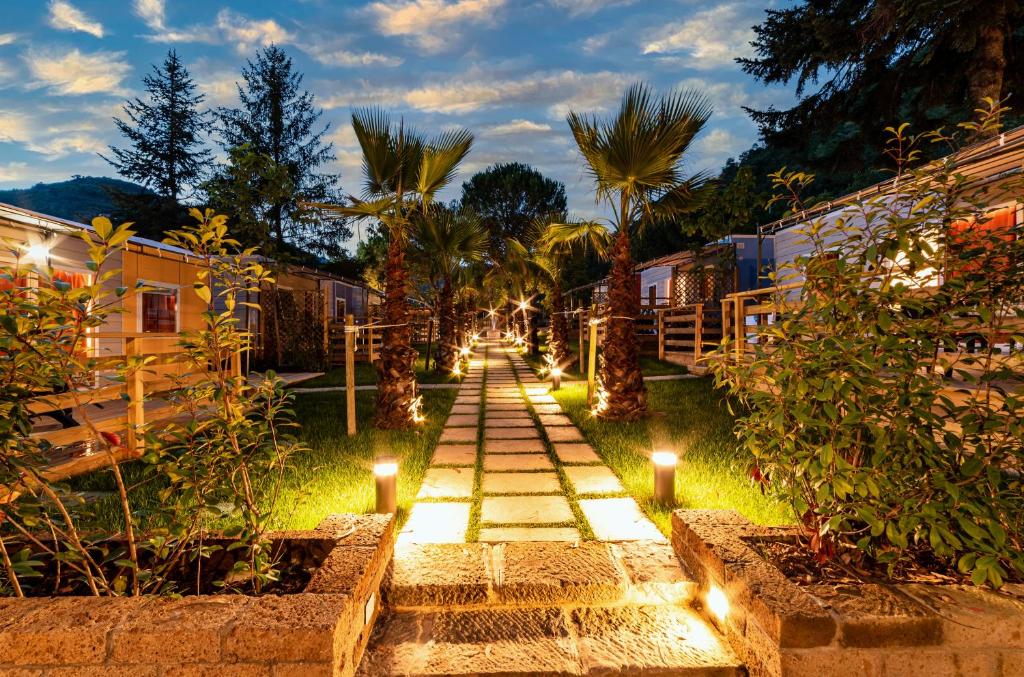 a pathway with lights in a garden at night at Delle Rose Camping & Glamping Village in Isolabona