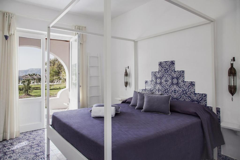 a bedroom with a large bed with a purple bedspread at Mari del Sud Resort in Vulcano