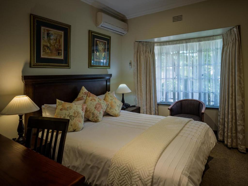 a bedroom with a bed and a desk and a window at Gallo Manor Executive Bed & Breakfast in Johannesburg