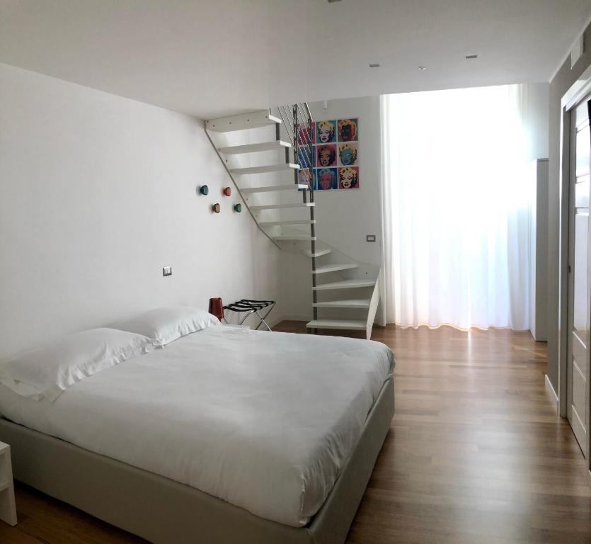 ein weißes Schlafzimmer mit einem Bett und einer Treppe in der Unterkunft Lo Schiaccianoci B&B in Taranto