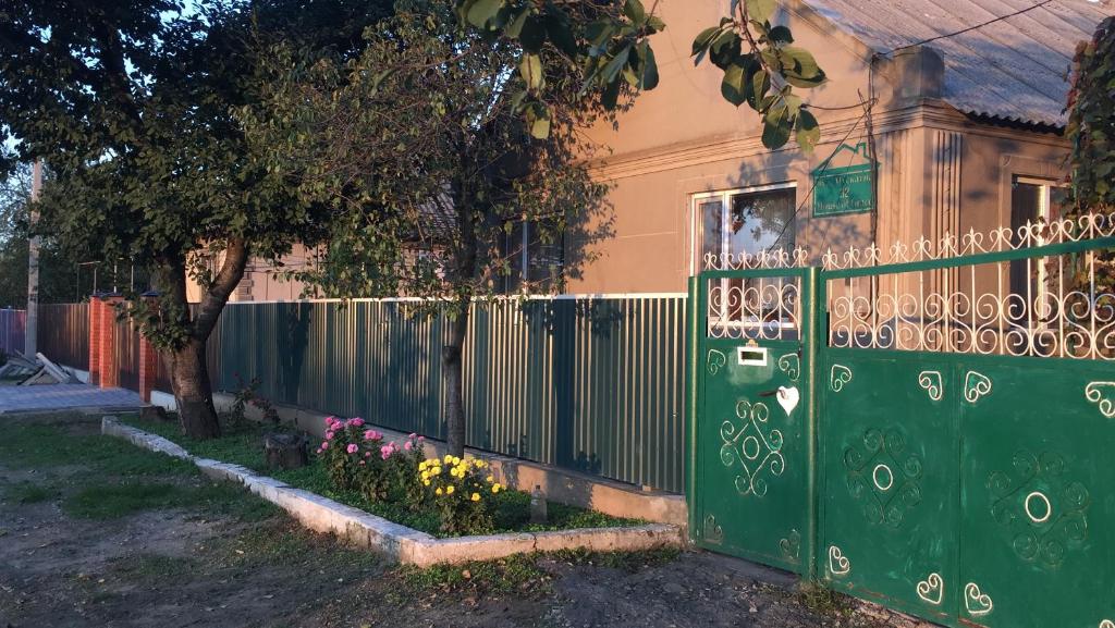 a green fence in front of a house with flowers at House of Grace in Reni